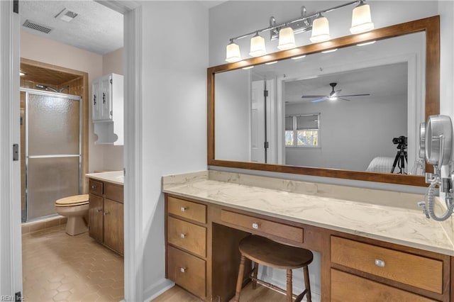 bathroom with vanity, ceiling fan, toilet, a shower with door, and tile patterned floors