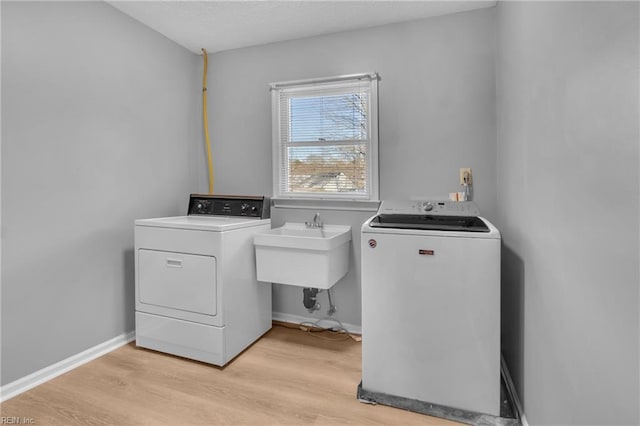 laundry room with separate washer and dryer, sink, and light wood-type flooring