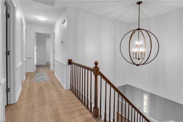 hall with light hardwood / wood-style floors and a notable chandelier