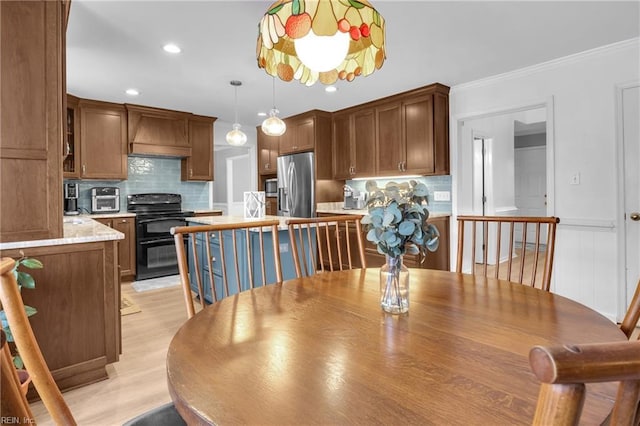 dining space featuring ornamental molding and light wood-type flooring