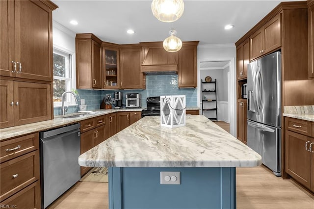 kitchen featuring appliances with stainless steel finishes, pendant lighting, sink, a center island, and custom range hood