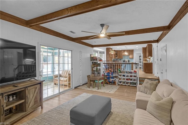 living room with beamed ceiling, ceiling fan, and light wood-type flooring