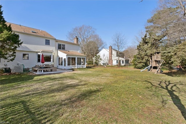 view of yard featuring a patio area, a sunroom, and a playground