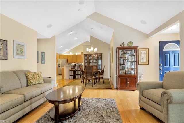 living room with light wood-type flooring, an inviting chandelier, and lofted ceiling