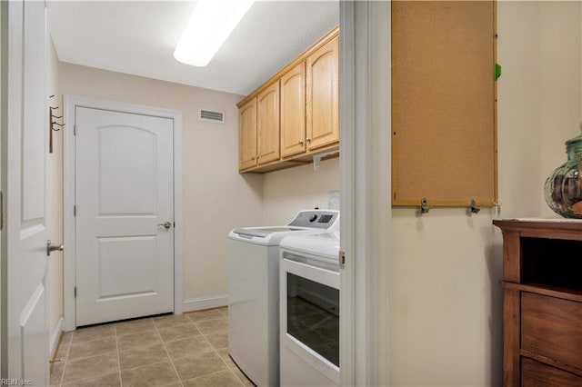 clothes washing area with cabinets, light tile patterned floors, and washing machine and dryer