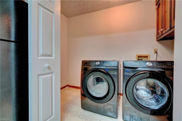 clothes washing area featuring cabinets and separate washer and dryer