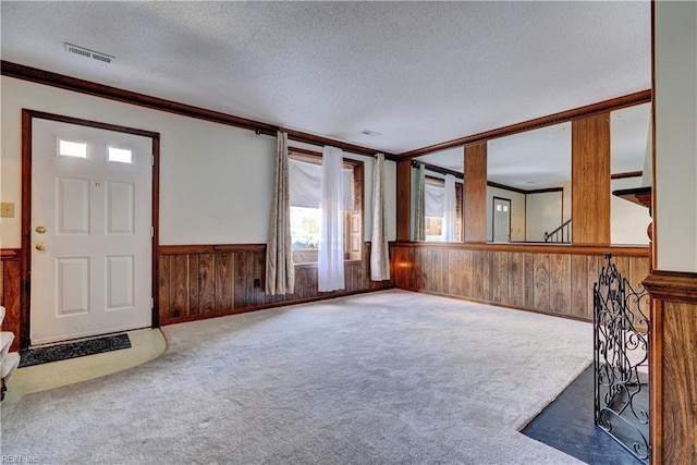 carpeted foyer entrance featuring a textured ceiling and crown molding