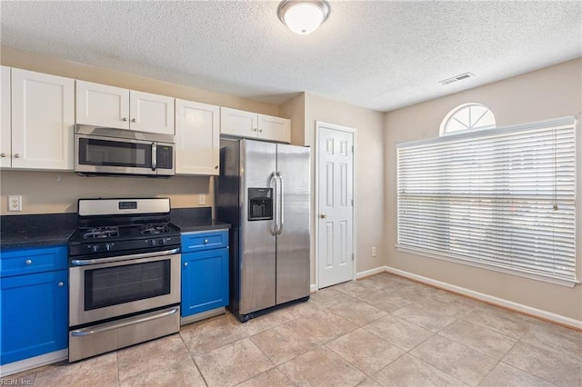 kitchen featuring stainless steel appliances, light tile patterned flooring, blue cabinets, and white cabinets