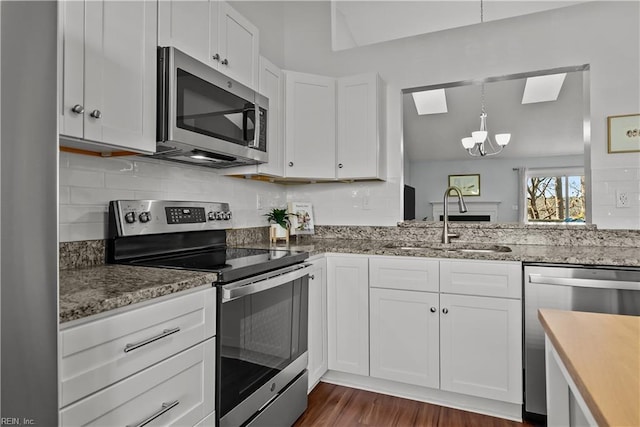 kitchen with sink, white cabinetry, dark hardwood / wood-style flooring, stainless steel appliances, and decorative backsplash