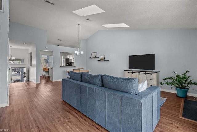 living room featuring vaulted ceiling, a chandelier, and hardwood / wood-style floors