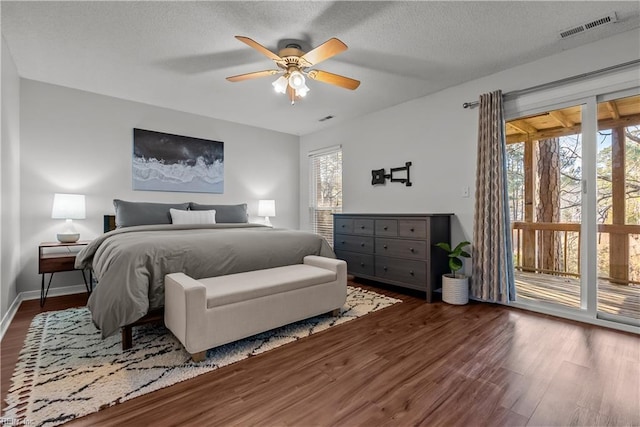 bedroom featuring dark hardwood / wood-style flooring, access to outside, a textured ceiling, and ceiling fan