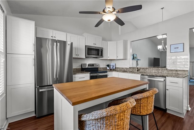 kitchen featuring white cabinets, appliances with stainless steel finishes, lofted ceiling, and kitchen peninsula