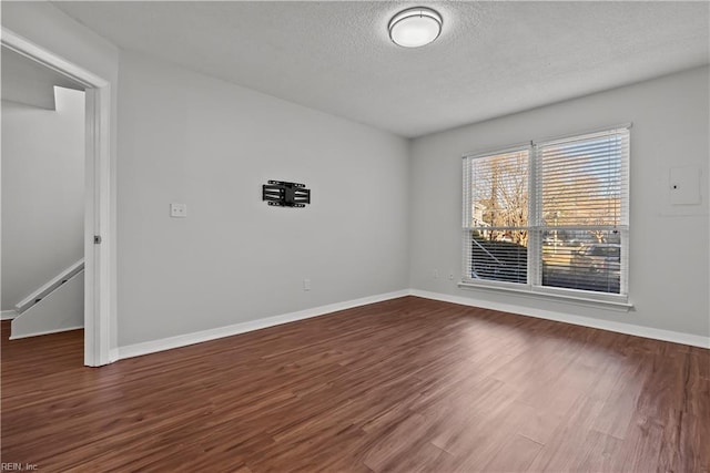 spare room featuring dark hardwood / wood-style flooring and a textured ceiling