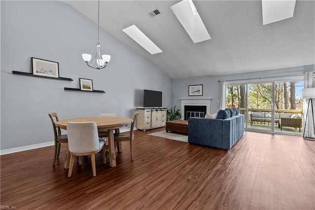 dining room with high vaulted ceiling, dark hardwood / wood-style floors, a chandelier, and a skylight