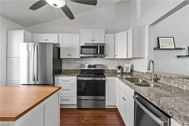 kitchen with vaulted ceiling, tasteful backsplash, sink, white cabinets, and stainless steel appliances