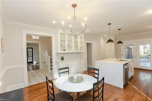 dining space with sink, crown molding, and french doors