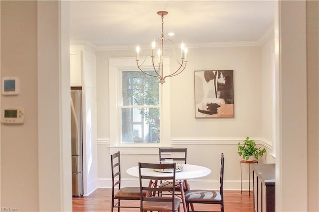 dining space featuring crown molding, hardwood / wood-style floors, and a notable chandelier