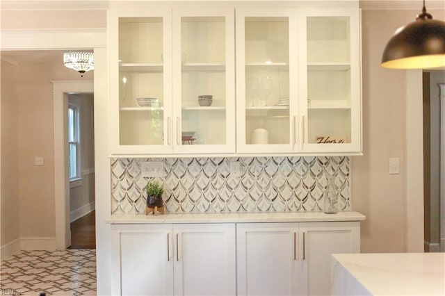 bar featuring backsplash, hanging light fixtures, and white cabinets