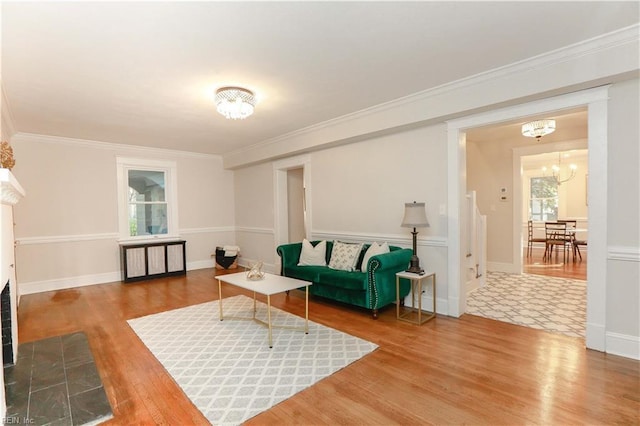 living room featuring hardwood / wood-style flooring, crown molding, a fireplace, and an inviting chandelier