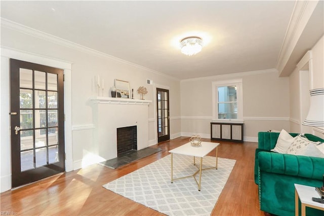 living room featuring hardwood / wood-style flooring, ornamental molding, a fireplace, and french doors