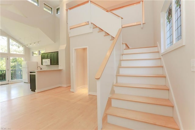 stairway featuring a high ceiling and hardwood / wood-style floors