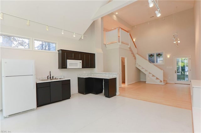 kitchen featuring white appliances, sink, and high vaulted ceiling