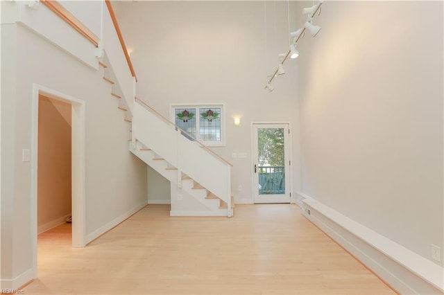 foyer entrance with a high ceiling and light hardwood / wood-style floors