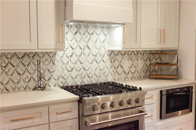 kitchen with white cabinetry, gas stove, light stone counters, and decorative backsplash