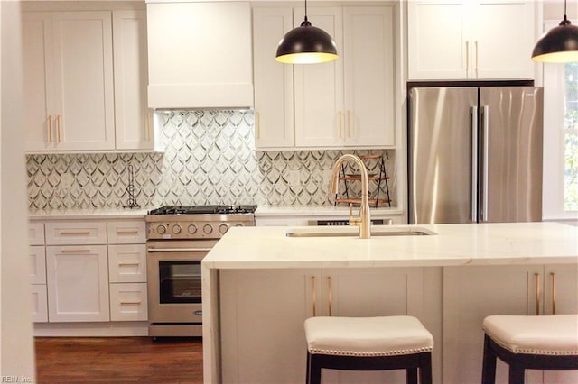 kitchen featuring sink, premium range hood, appliances with stainless steel finishes, tasteful backsplash, and decorative light fixtures