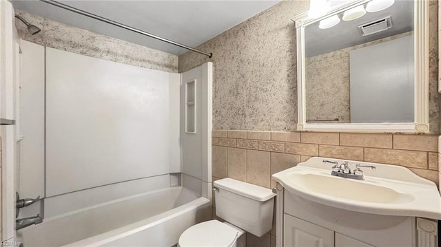 full bathroom with vanity, toilet, tub / shower combination, and tile walls