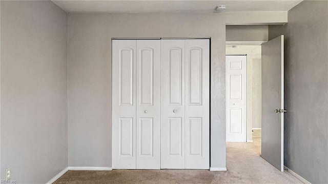 unfurnished bedroom with light carpet and a closet