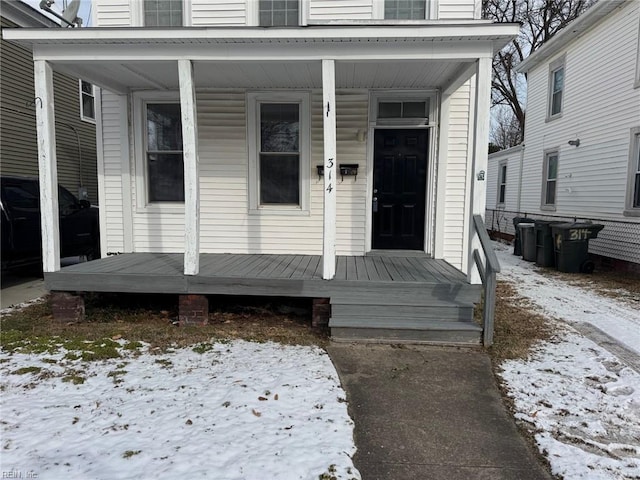 snow covered property entrance featuring a porch