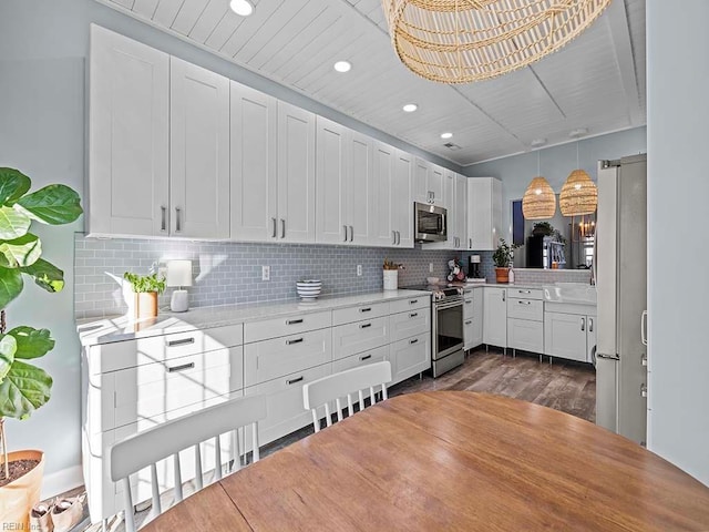 kitchen featuring white cabinets, backsplash, appliances with stainless steel finishes, and dark hardwood / wood-style flooring