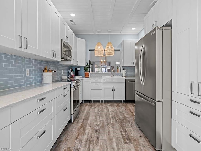 kitchen featuring decorative light fixtures, sink, white cabinetry, and appliances with stainless steel finishes