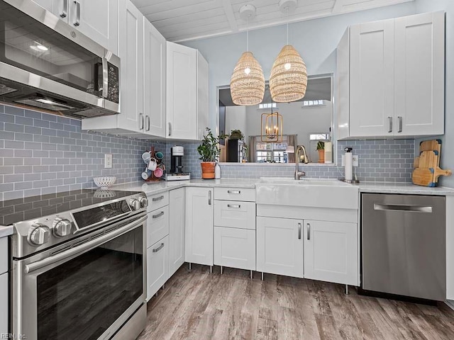 kitchen with white cabinets, stainless steel appliances, and hanging light fixtures