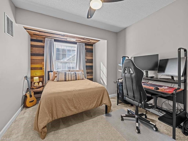 carpeted bedroom featuring wood walls, a textured ceiling, and ceiling fan