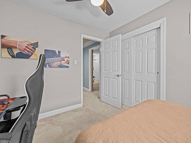 bedroom with ceiling fan, a textured ceiling, a closet, and light carpet