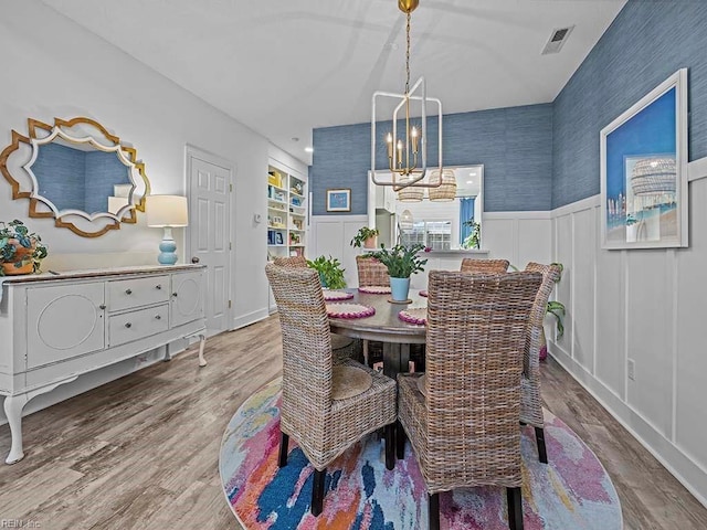 dining area with built in features, hardwood / wood-style floors, and a notable chandelier