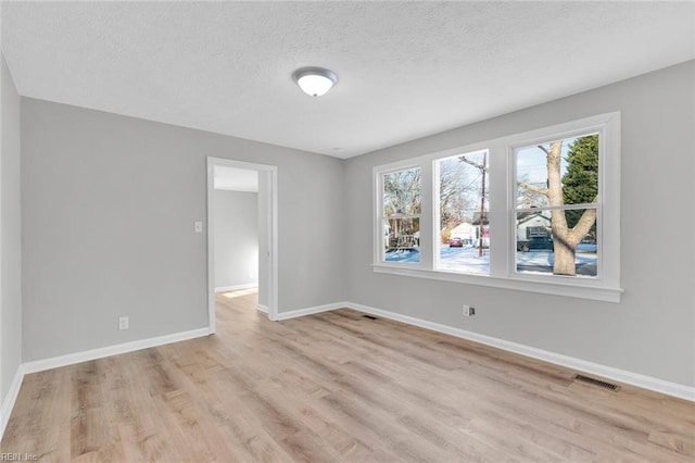 spare room featuring a textured ceiling and light hardwood / wood-style flooring