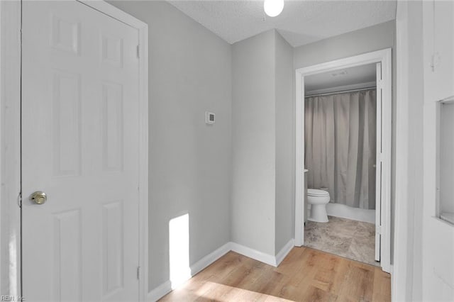 bathroom with wood-type flooring, toilet, and a textured ceiling