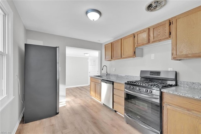 kitchen featuring light brown cabinets, light hardwood / wood-style flooring, sink, light stone countertops, and stainless steel appliances