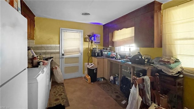 kitchen featuring separate washer and dryer, tile walls, and white fridge