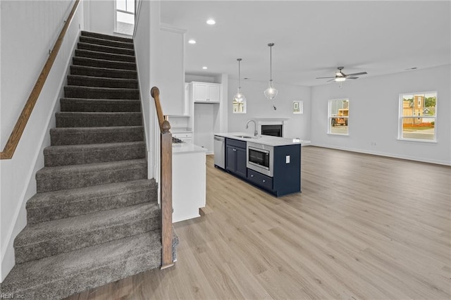 kitchen with blue cabinets, sink, decorative light fixtures, stainless steel appliances, and white cabinets