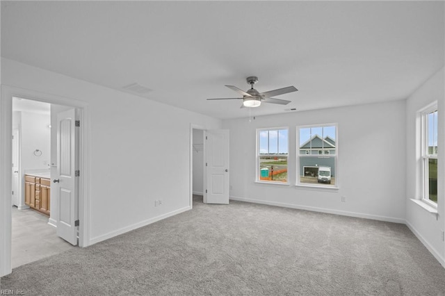 carpeted spare room featuring ceiling fan and a wealth of natural light