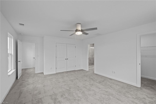 unfurnished bedroom with ensuite bathroom, light colored carpet, ceiling fan, and a closet