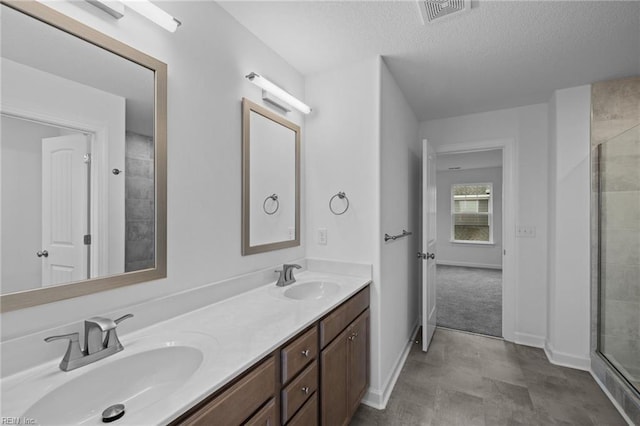 bathroom featuring vanity, a shower with shower door, and a textured ceiling