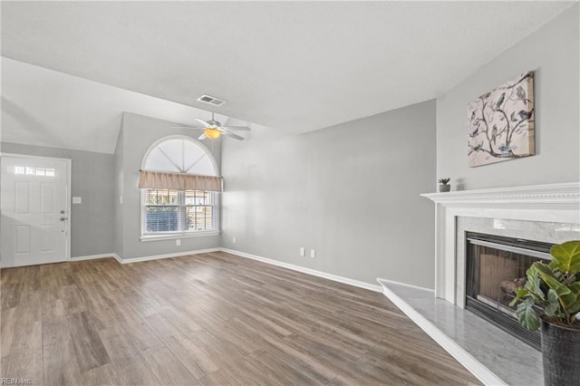 unfurnished living room featuring vaulted ceiling, hardwood / wood-style floors, ceiling fan, and a fireplace