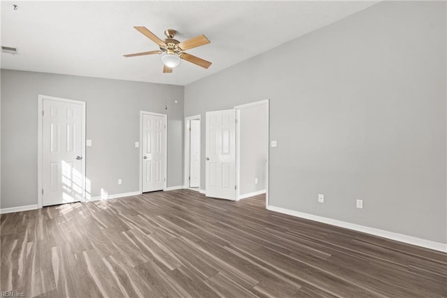 unfurnished bedroom featuring multiple closets, vaulted ceiling, dark hardwood / wood-style floors, and ceiling fan