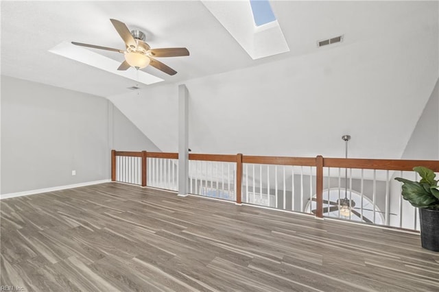 unfurnished room featuring ceiling fan, wood-type flooring, and lofted ceiling with skylight