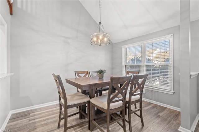 dining area featuring vaulted ceiling, a chandelier, and light hardwood / wood-style floors